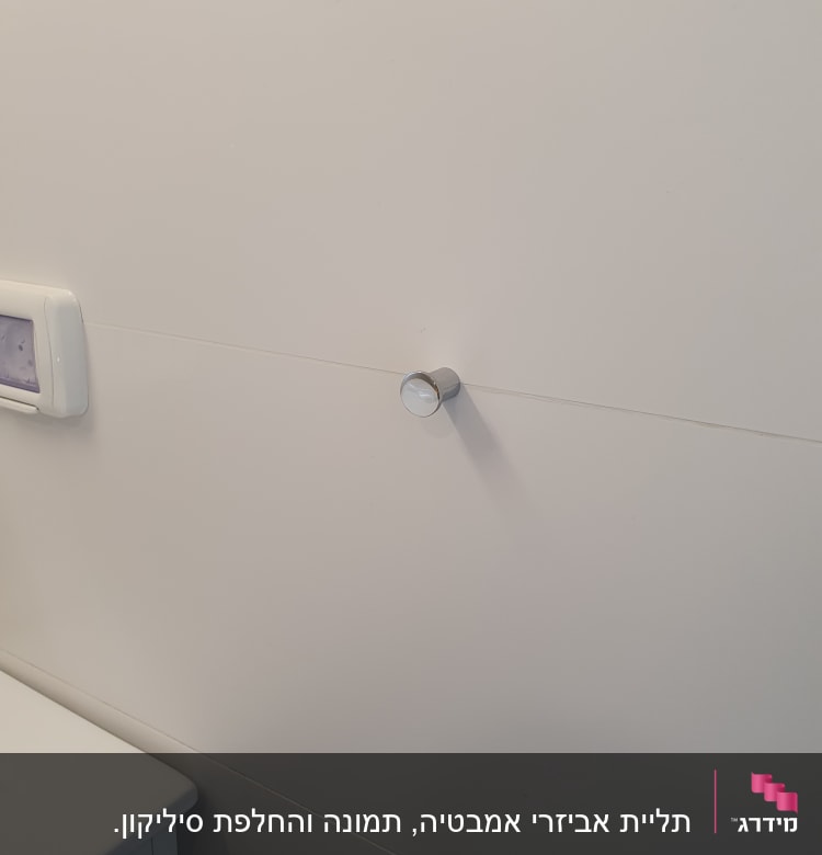 ידית מתכת עגולה מותקנת על קיר לבן